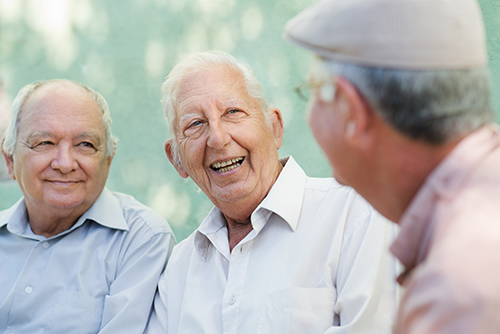 Three elderly men sitting outside chatting